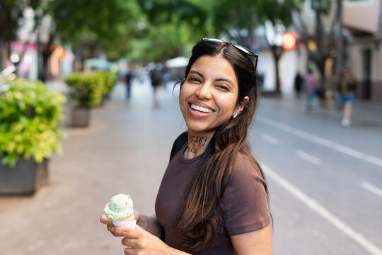 Happy Young Woman Enjoys Ice Cream on a City Street in the Afternoon