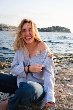 A woman is enjoying some time on the shore, laughing in the sunshine