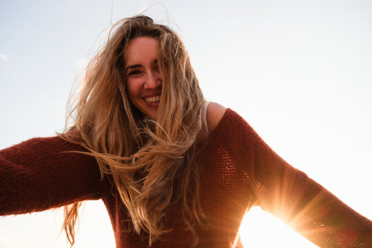 A smiling woman enjoys a sunny day outdoors. Copy space, blue sky