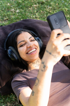 Woman Enjoys Leisure Time Listening to Music in a Park