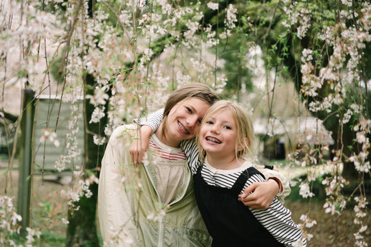 Two happy girls under a cherry tree in bloom