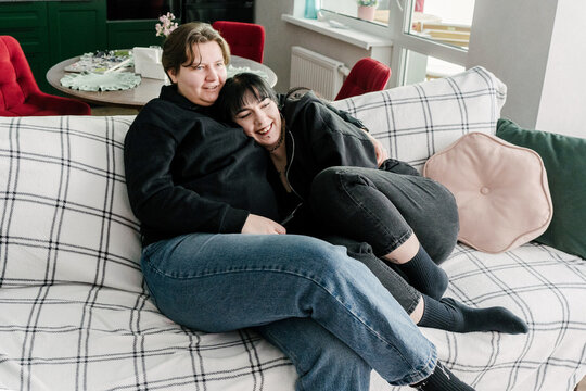 Two young women are relaxing at home on a cozy sofa.