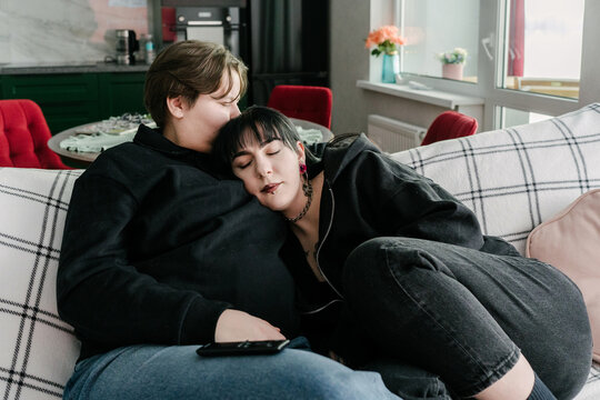 Two young women are having a cozy time on the couch.