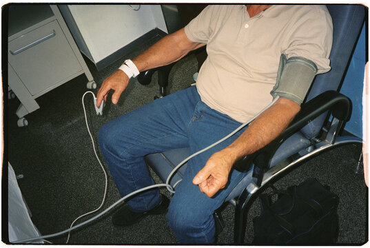 Man in a chair wearing a blood pressure cuff and pulse oximeter.