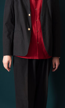 Model Standing in Red Shirt and Black Suit with Emerald Backdrop