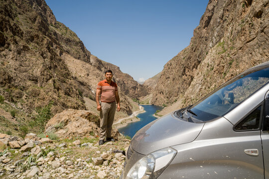 Guide Stands Near Lake in Mountain Valley While His Car is Parked