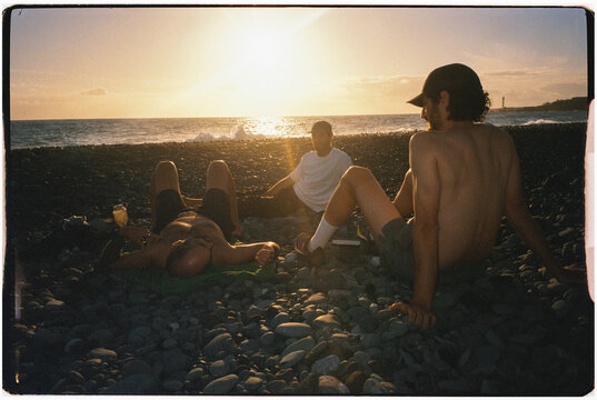 Friends enjoy a sunset on the rocky beaches of La Palma.