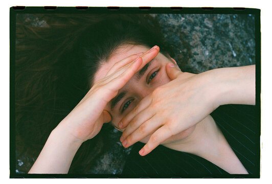 A young woman lying down, hands covering her face