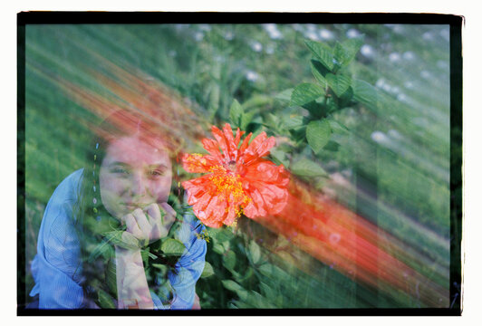 A woman and a hibiscus bloom merge in a double exposure