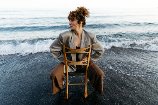 Woman posing on chair in sea water