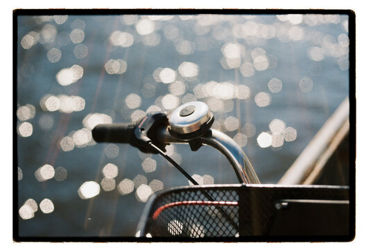 A bicycle bell and handlebar parked beside shimmering water