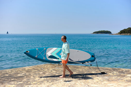 Man Carrying Paddle Board by the Sea
