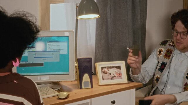 Diverse young adults troubleshooting vintage desktop computer, connecting cables and inserting floppy disk. Ideal for nostalgic technology commercials or retro IT support advertisements