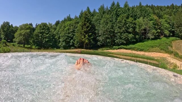 Female feet in a hot tub and whirlpool facing the woods