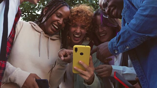 Diverse friends laughing together watching smartphone