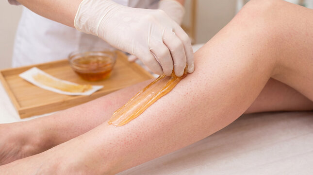 Beautician Applying Sugar Wax to Woman&rsquo;s Leg for Hair Removal Treatment