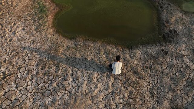 man sitting by dried pond el nino water crisis rural impact