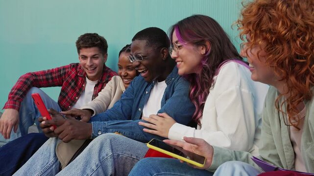Diverse group of friends laughing together while using smartphone