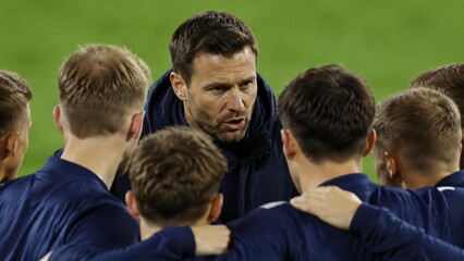 Fototapeta premium A sport trainer leads a team of young men in a huddle on a green field, promoting unity, motivation, and strategy.