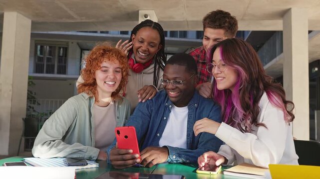 Diverse group of friends laughing together at smartphone