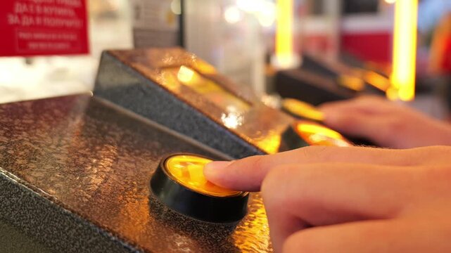 Player pressing a yellow button on arcade game console
