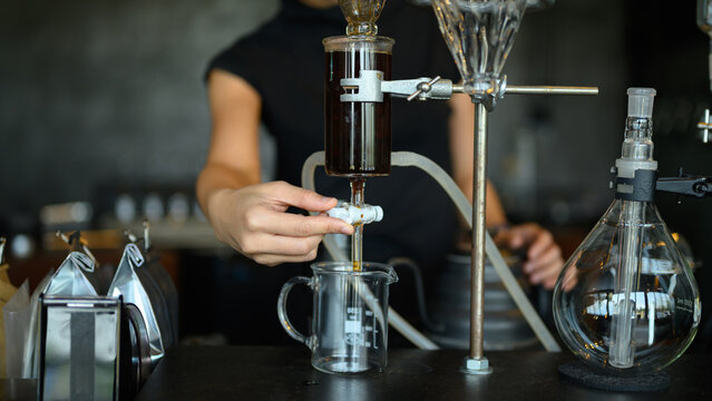 Barista Operating Laboratory-Style Cold Drip Coffee Brewing Apparatus in Specialty Cafe