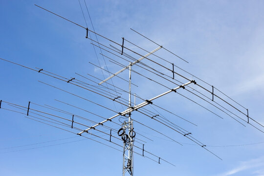 Tall antenna masts rising against a clear blue sky. Radio amateur equipment used for long-distance communication. A view of tall antenna masts against the clear blue sky.