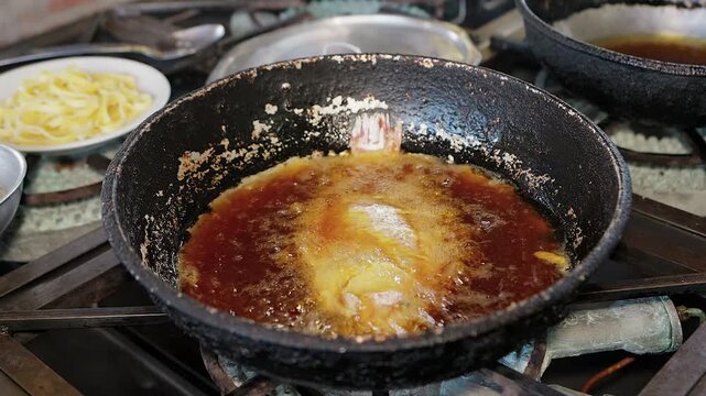 deep frying whole fish in a large pan with hot oil in restaurant kitchen