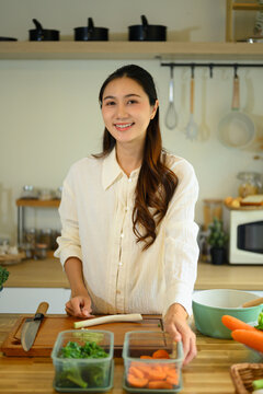 Smiling Young Woman Preparing Fresh Vegetables in a Modern Home Kitchen