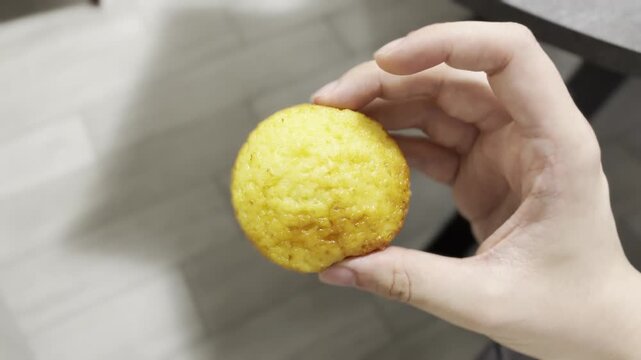Hand Holding a Homemade Muffin Indoors