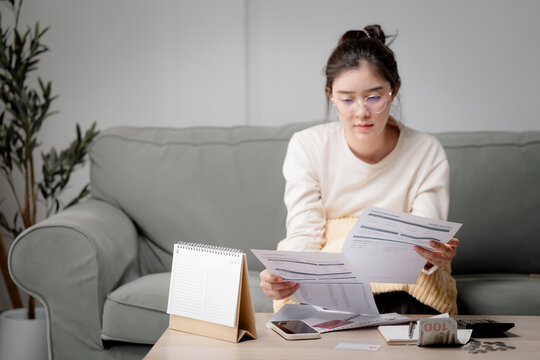 Online bill payment and personal finance. Woman checks an invoice on a smartphone while reviewing a utility bill at home. Invoice, payment, finance, billing and budgeting concept
