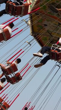 Visitors of the amusement park are enjoying the wave swinger ride. Visitors are excited to try the swing ride at the amusement park