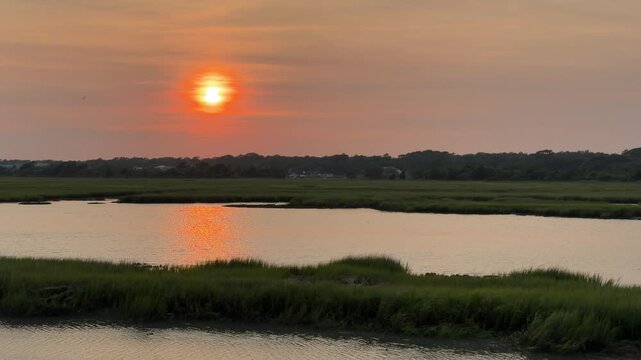 Establishing shot of a gorgeous sunset across an inlet at the beach with copy space