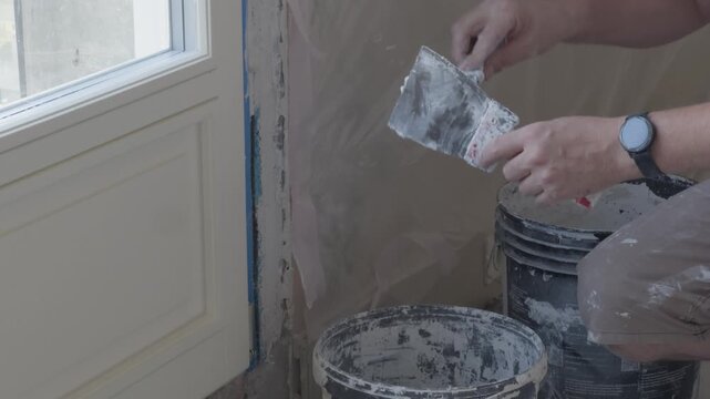 construction worker applying plaster on wall with putty knife