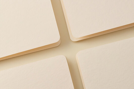 Close up view of four cream colored square cards overlapping corners