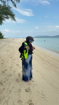 A young woman on the beach is preparing to go swimming with snorkeling gear on a sunny day