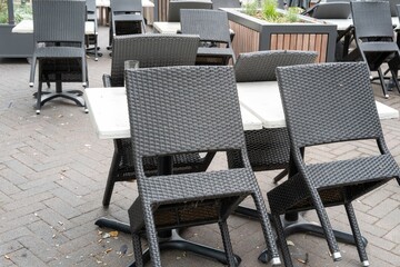 Empty tables and chairs stacked upside down in an outdoor seating area at a cafe outside of business hours © Ulrich
