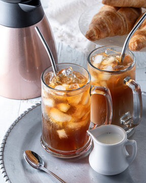 Glasses of iced coffee on a tray, served with cream and croissants.