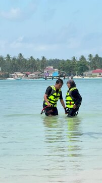 A young couple on the beach is preparing to go swimming with snorkeling gear on a sunny day