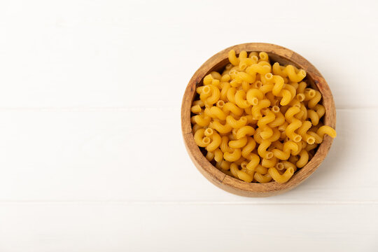 Raw Cavatappi pasta on a wooden table. tasty raw Cavatappi. close-up. Banner. Raw pasta in a jar, wooden spoon. Raw Italian pasta, European cuisine.  Design. 