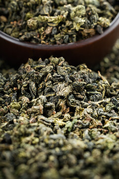 Dark wooden bowl filled with Tieguanyin on tea texture background