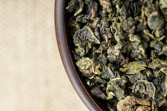 Macro overhead shot premium loose tea in wooden cup on linen like fabric