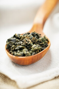 Macro overhead shot premium loose tea in wood spoon on natural fabric