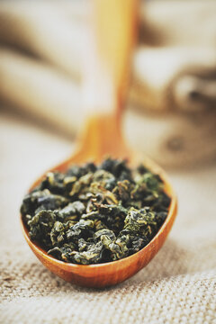 Top view closeup rustic spoon filled with loose tea on craft fabric