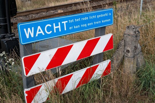 Sign warns of train crossing in the netherlands while people wait for red light to stop