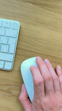 Finger clicking a mouse while scrolling forward and back. Vertical view of hand navigating with a trackpad gesture. Close-up moment of everyday computer control at a desk..