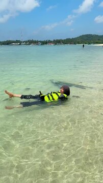 A young woman on the beach is preparing to go swimming with snorkeling gear on a sunny day