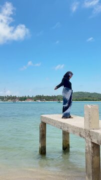 A young woman on a beach pier in Kotabaru, gazing out at the sea