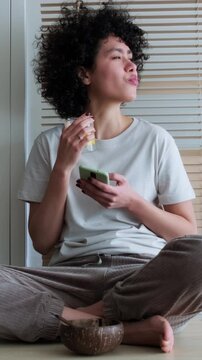 Young woman enjoying healthy breakfast while using smartphone