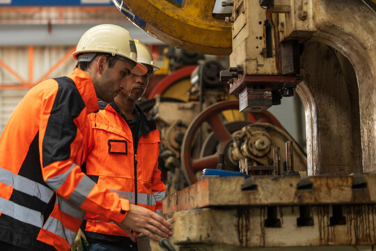 Male manufacturing in high visibility jacket and hard hat operator managing machine.
